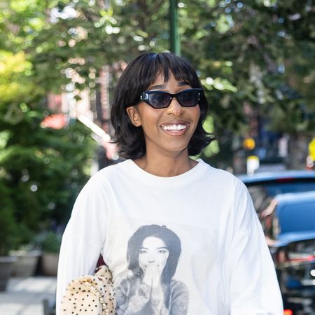 Ayo Edebiri wearing a white longsleeve Bkork graphic T-shirt, black tailored pants, and black thong sandals