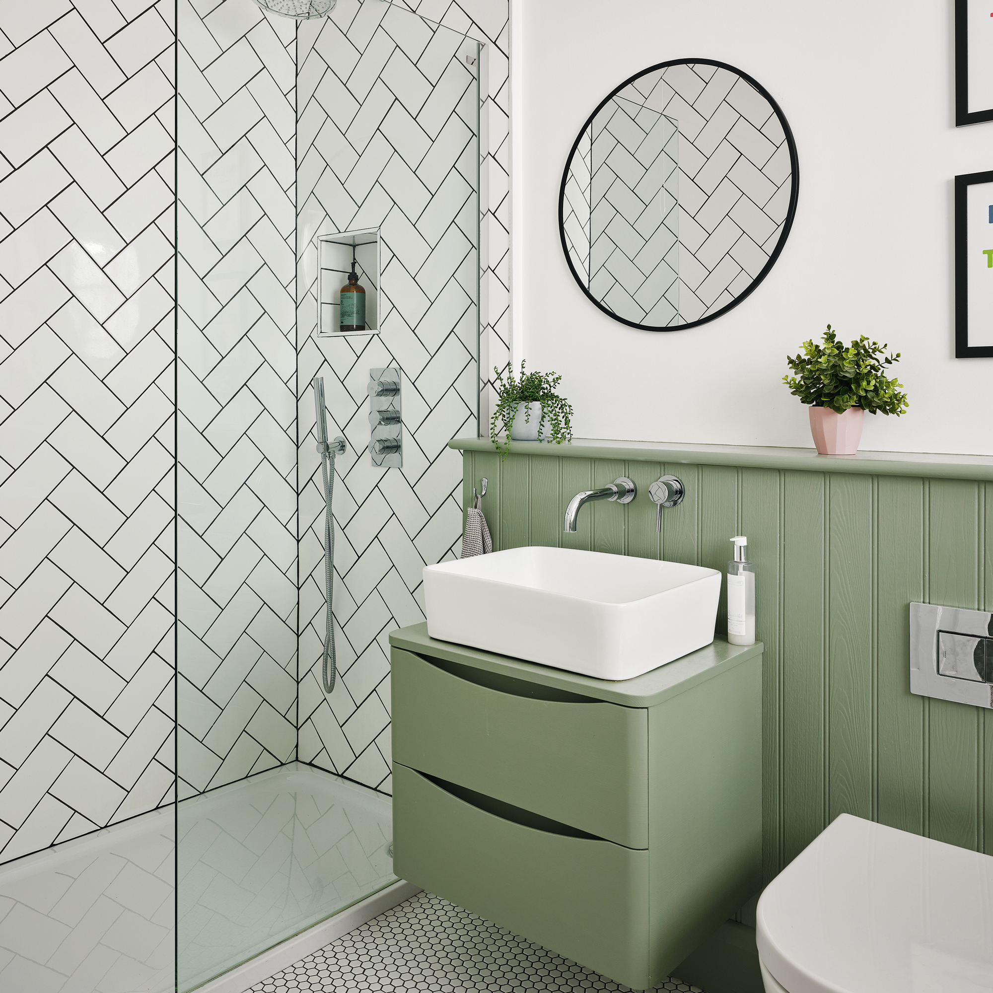 a green and white bathroom with painted green panelling, a shower area with white metro tiling and a green floating vanity unit
