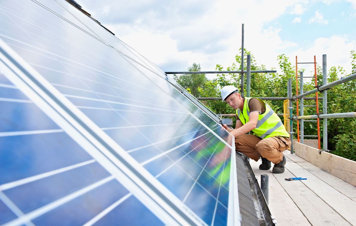 Man installing solar panels on roof