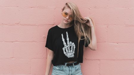 Photo of female model wearing a T-shirt with design of skeletal hand making the peace sign.