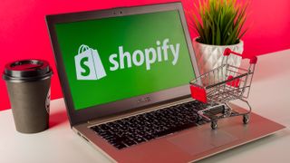 Shopify logo displayed on a modern laptop on desk with cart