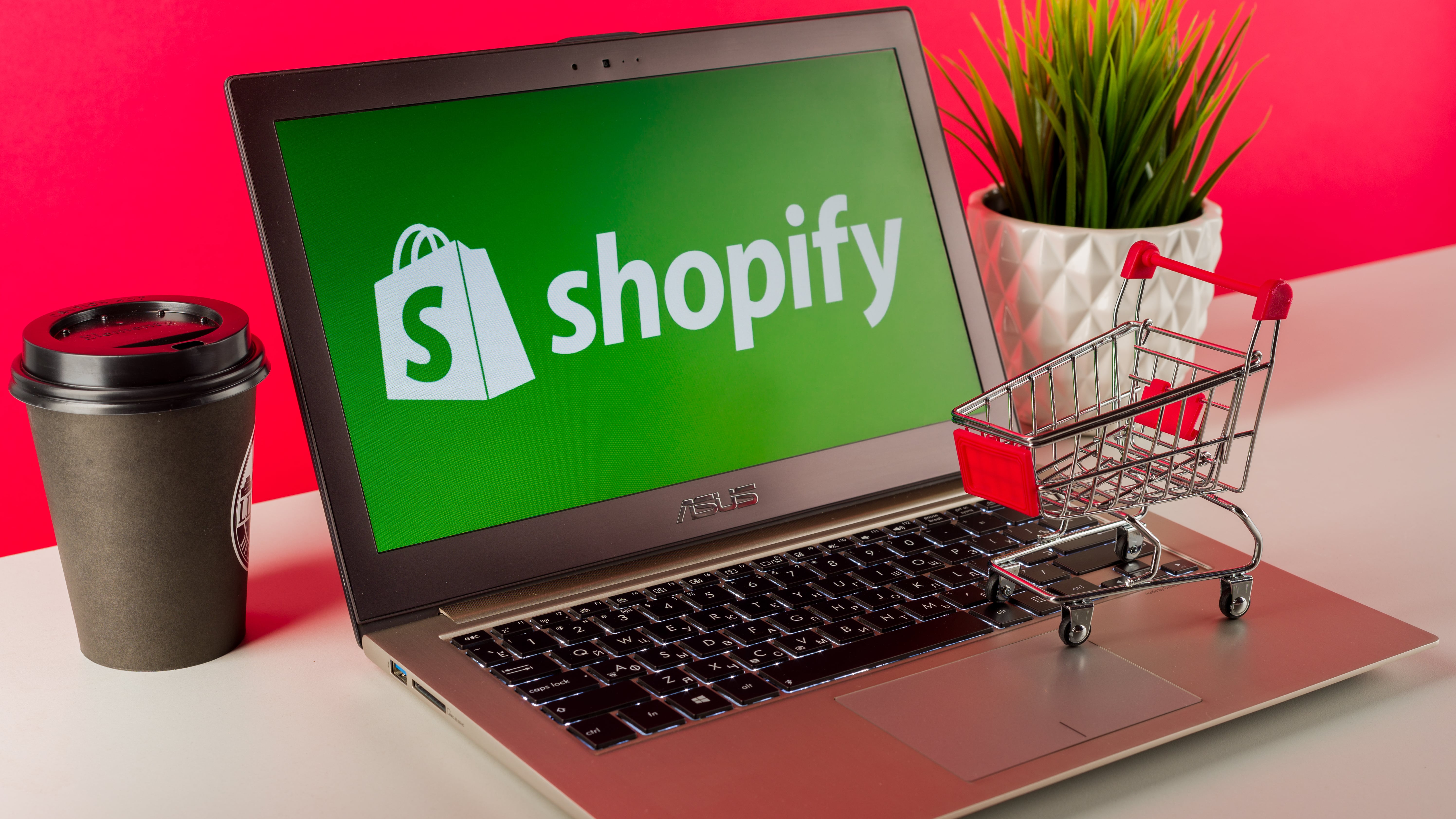 Logo Shopify ditampilkan pada laptop modern di atas meja dengan keranjang