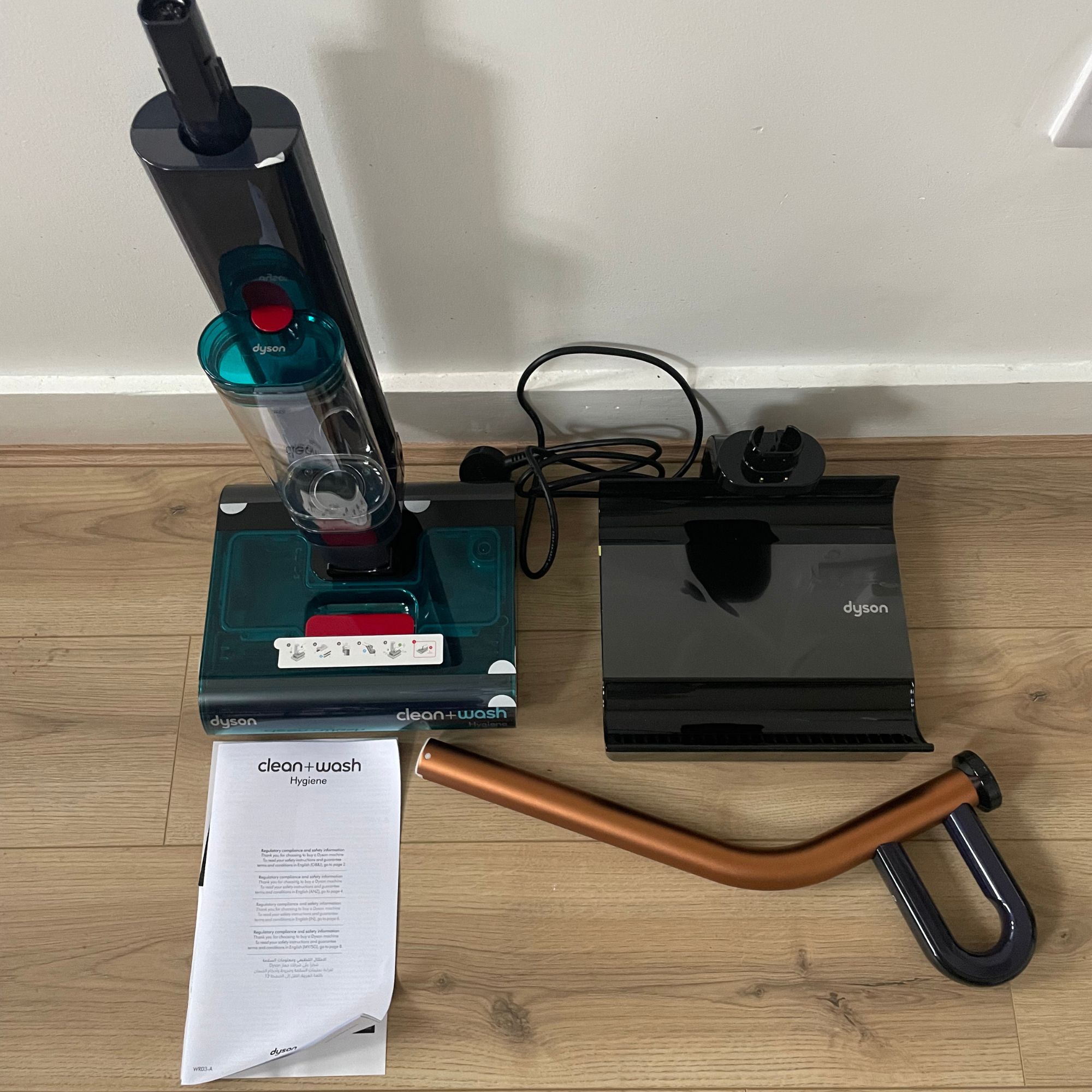 Dyson Clean+Wash Hygiene components laid out on wood-effect flooring