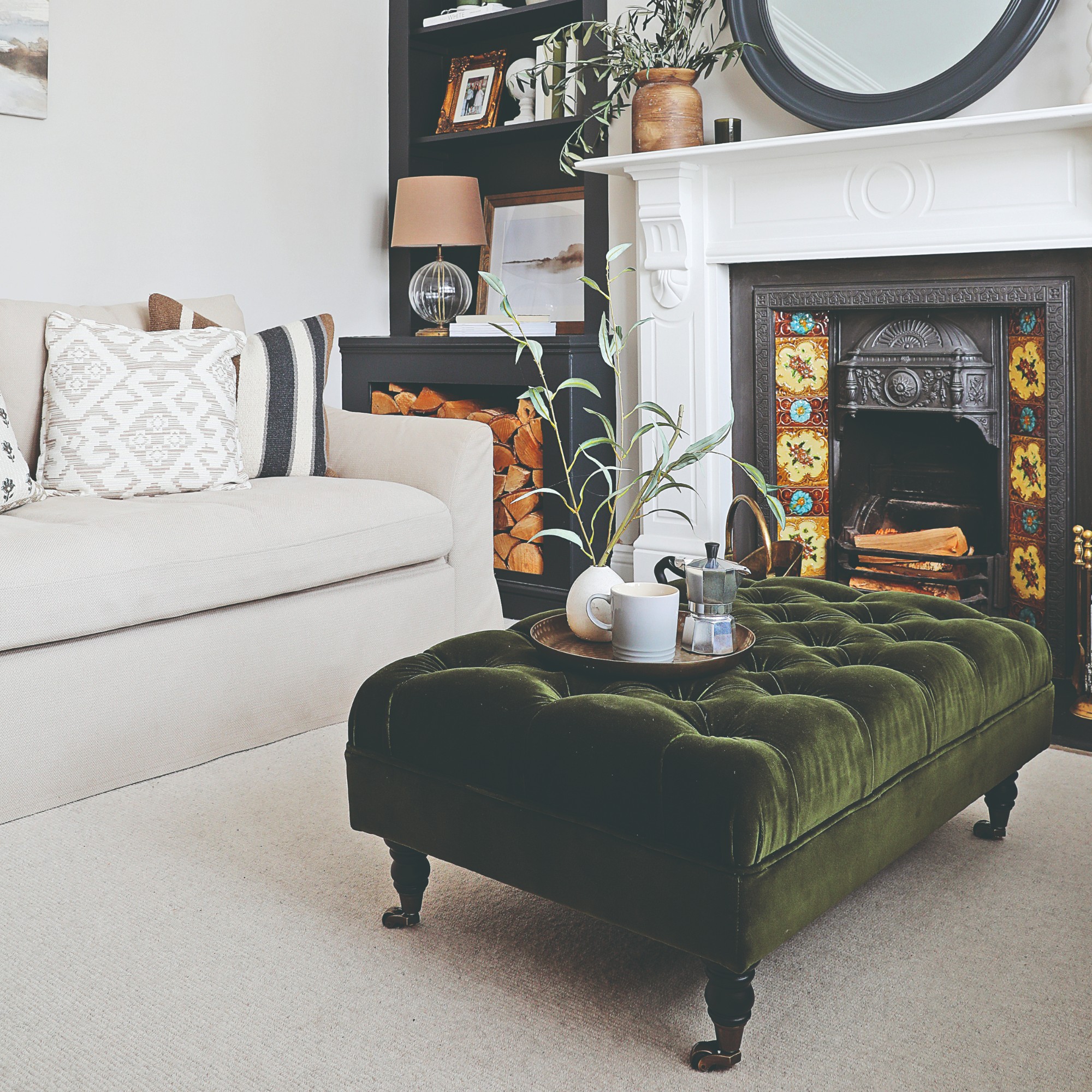 A living room with a loose-cover cream sofa with a button-back green velvet ottoman