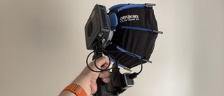 An Amaran Ray 120c being hand held, with a softbox fitted.