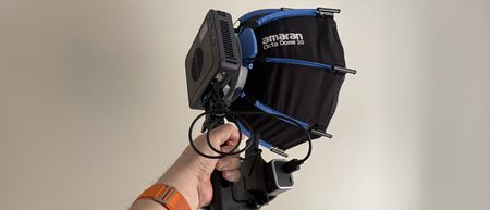 An Amaran Ray 120c being hand held, with a softbox fitted.