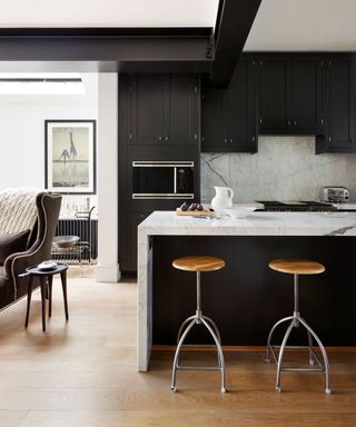 Grey kitchen ideas with marble backsplash and worktop, dark grey cabinetry and wooden bar stools