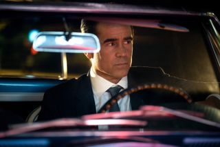 Colin Farrell dressed in a suit behind the wheel of a car