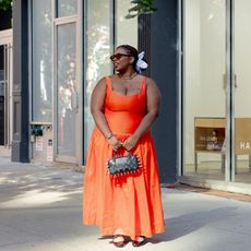 chichi wears red-orange dress, black slingbacks, blue flower hair scrunchie, and a black spiked bowler bag 