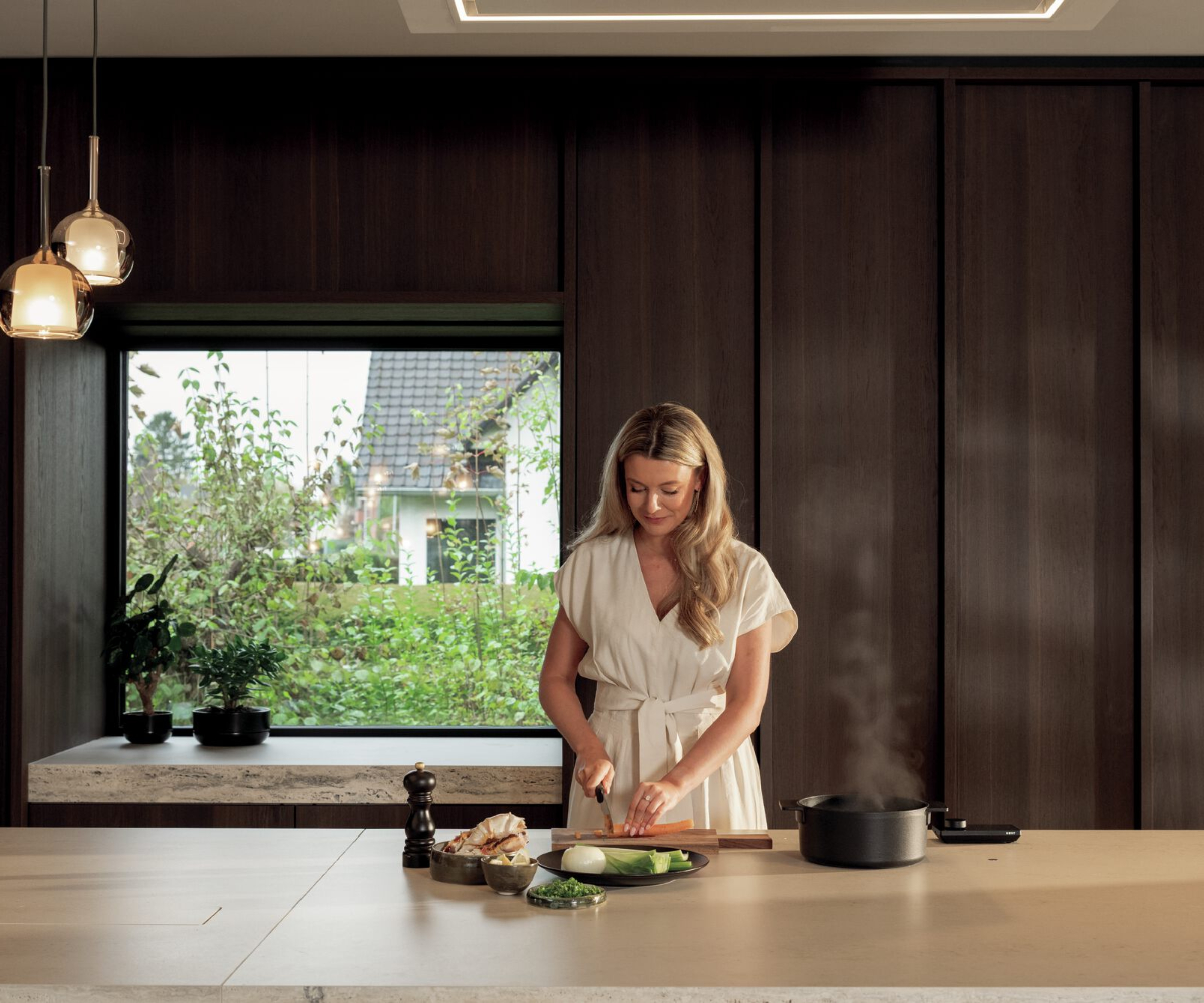 female stood cooking on kitchen worktop with hidden induction hob