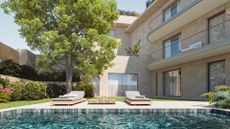 A backyard with sun loungers under a tree and by a pool