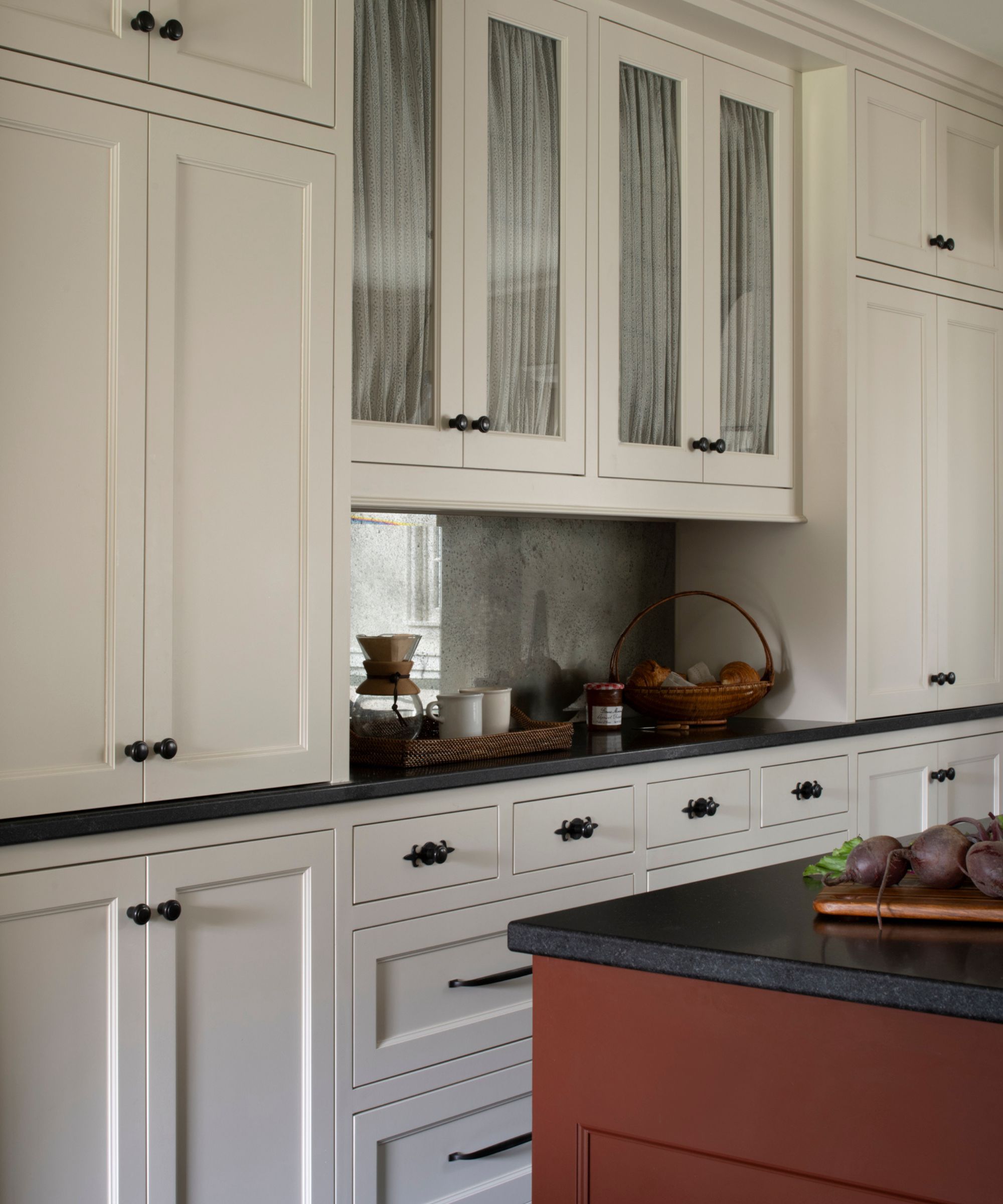 white farmhouse style kitchen with a mirrored backsplash, red kitchen island with dark countertops