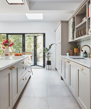 white shaker style kitchen with gold handles and a gold tap