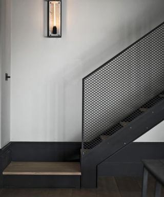 Black cage staircase railing idea by Nest with caged wall light
