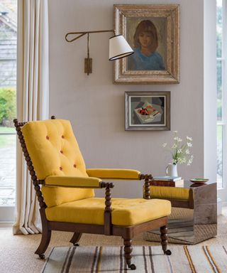 yellow armchair with a side table, gallery wall of art and a wall sconce
