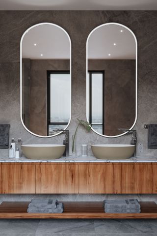 Bathroom with two freestanding basins and two long oval mirrors above them