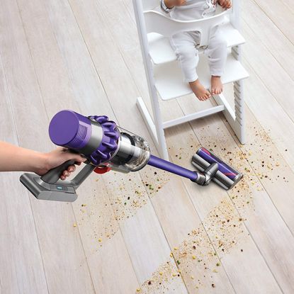 Which cordless vacuum cleaner? Dyson cordless vacuum vacuuming crumbs on floor near high chair