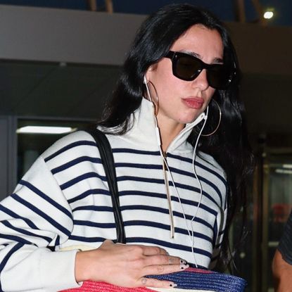 Dua Lipa arrived at the airport with Chanel's new oversized beach bag to match her coastal striped quarter-zip