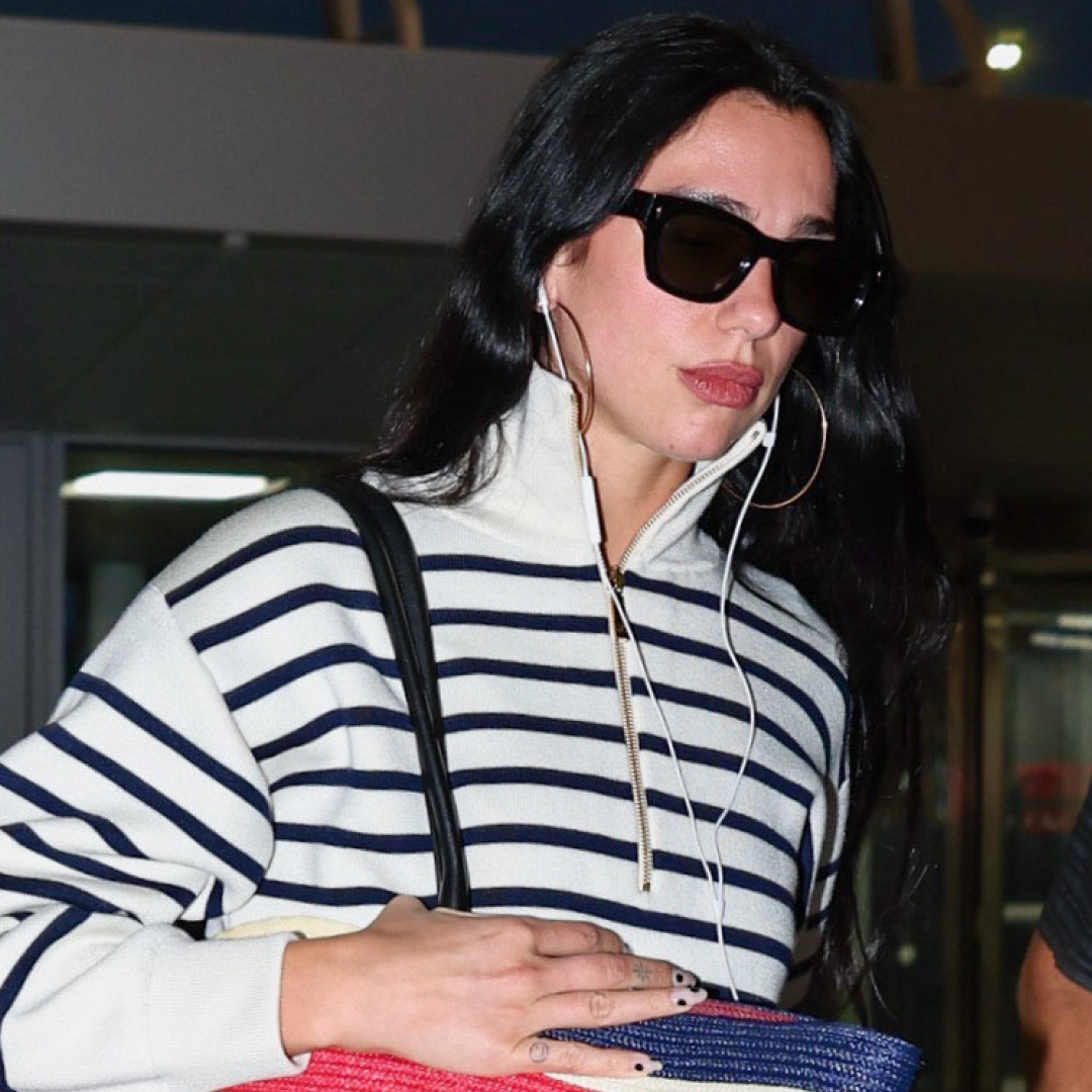 Dua Lipa arrived at the airport with Chanel's new oversized beach bag to match her coastal striped quarter-zip 
