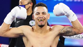 Robeisy Ramirez, wearing a mouthguard and white boxing gloves, flexes his muscles in celebrates prior to the Ramirez vs Espinoza live stream