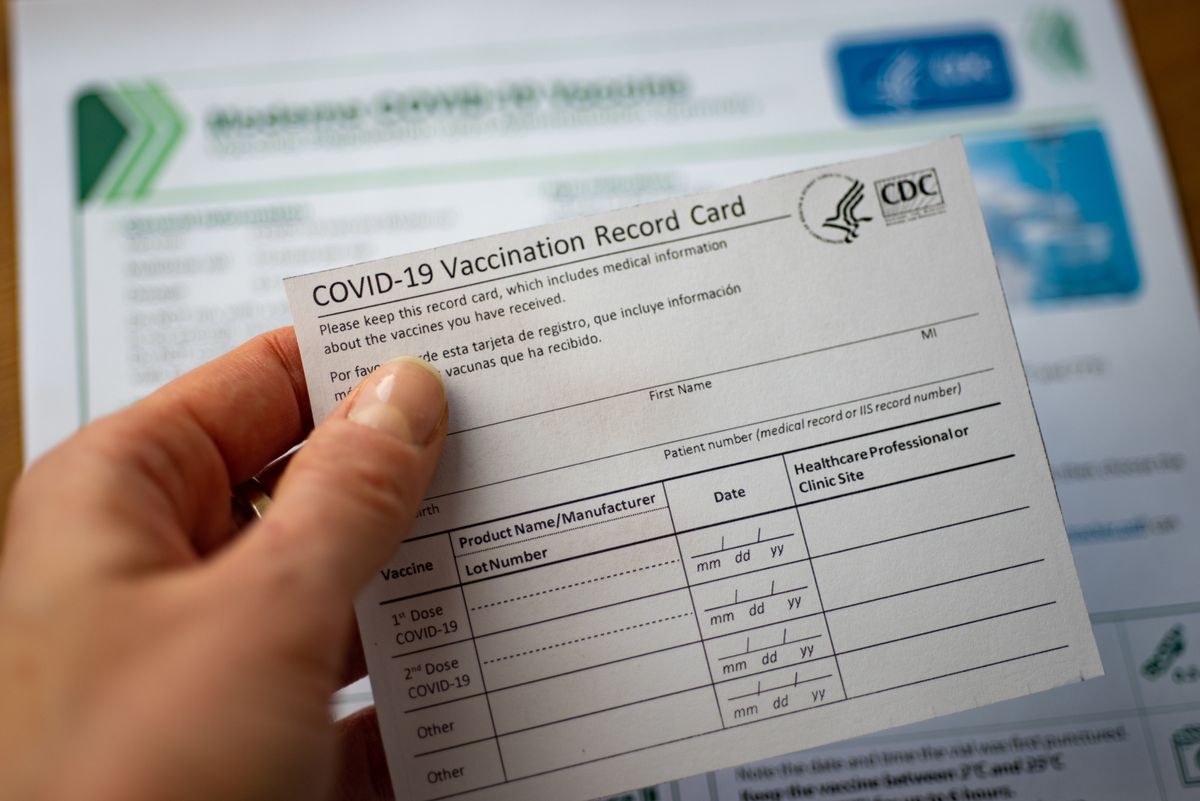 Woman&amp;#039;s hand holding a COVID-19 vaccination card