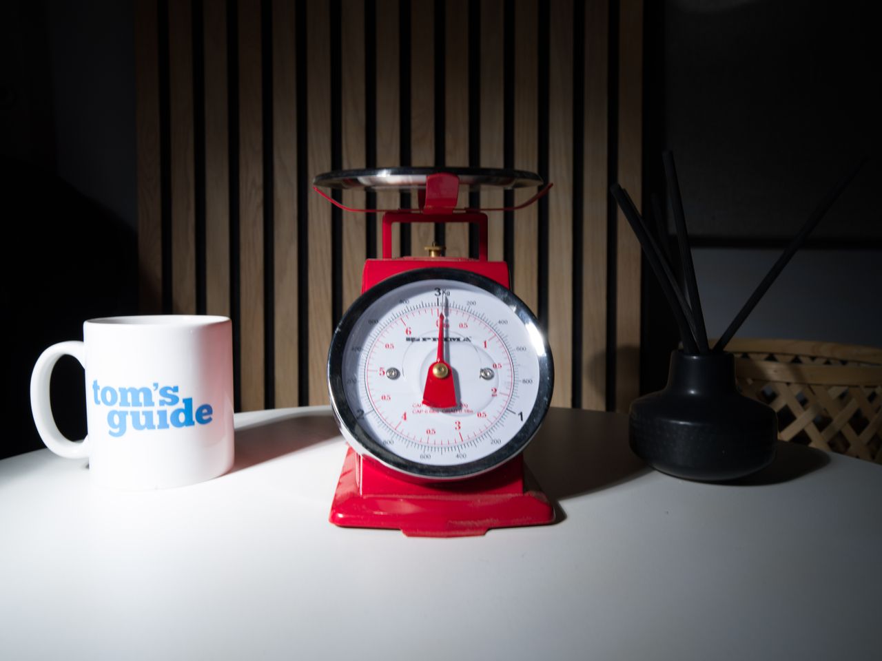 A photo of a set of red scales, with a Tom's Guide mug and a diffuser pot set either side.