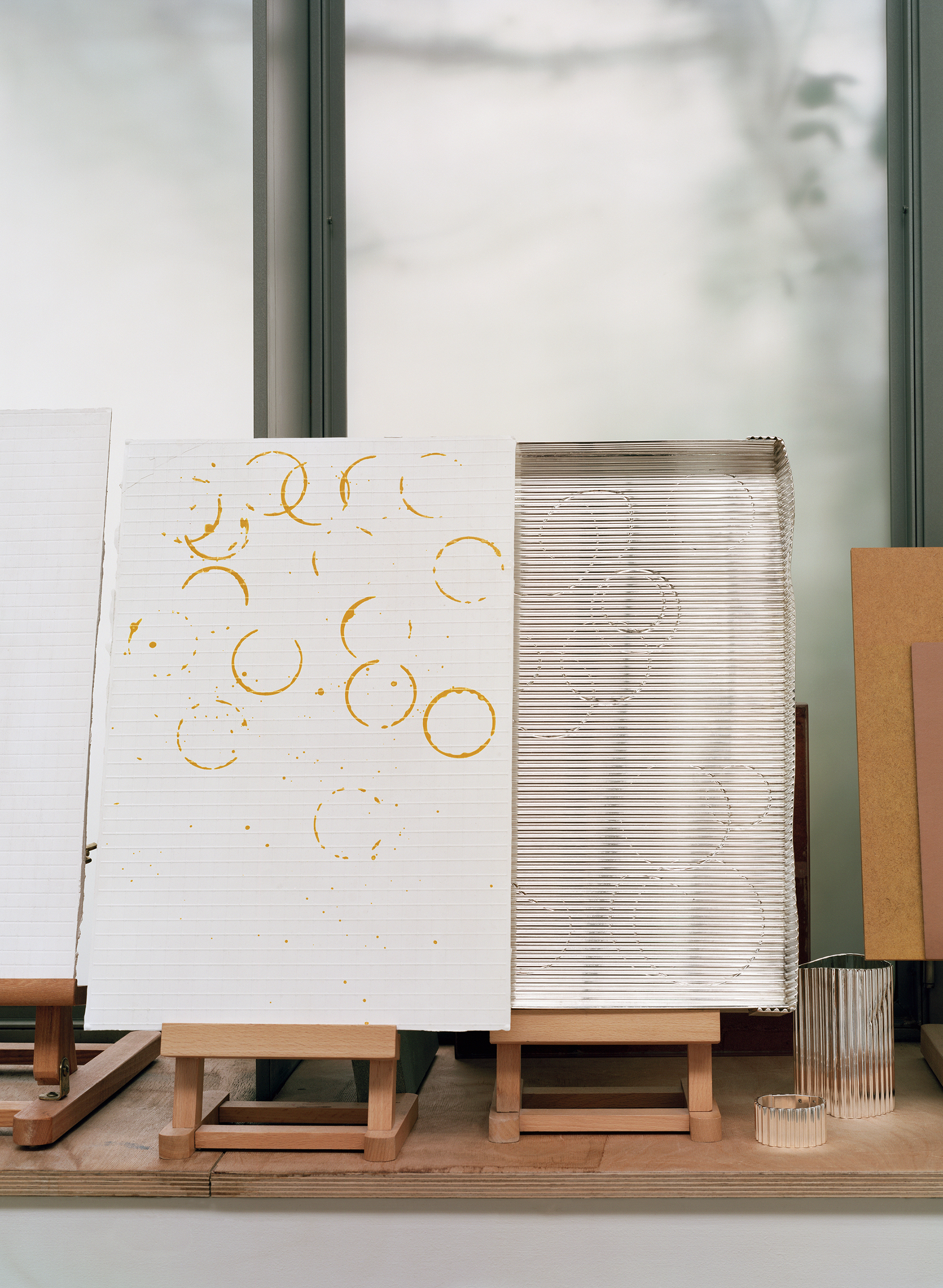 Silver objects with a ridged surface, shown in the context of a messy artist&#039;s studio