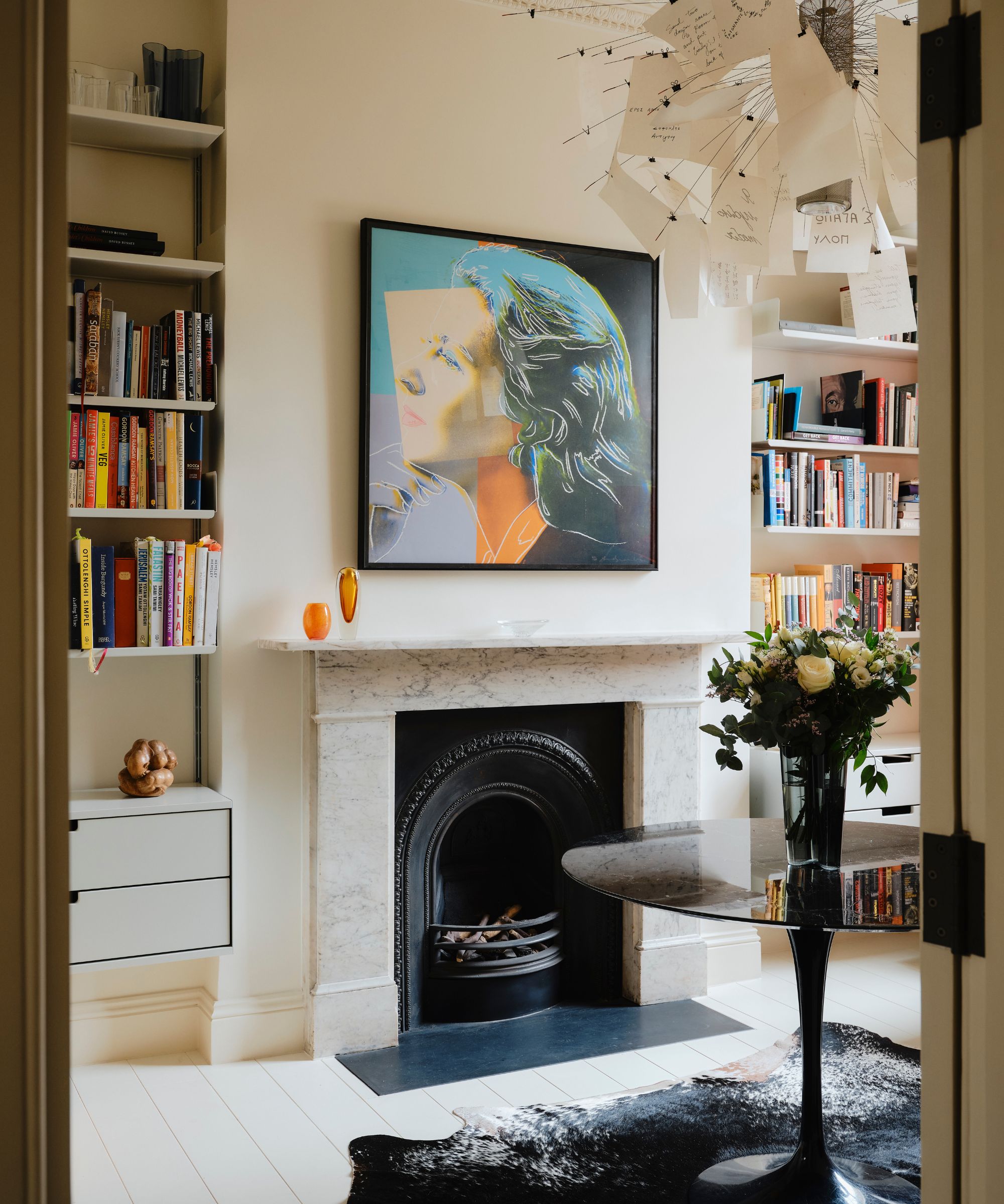Cream living room with marble fireplace with bookcases in alcoved and glass coffee table