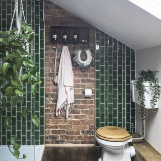 Green bathroom with exposed brick and towel storage next to shower