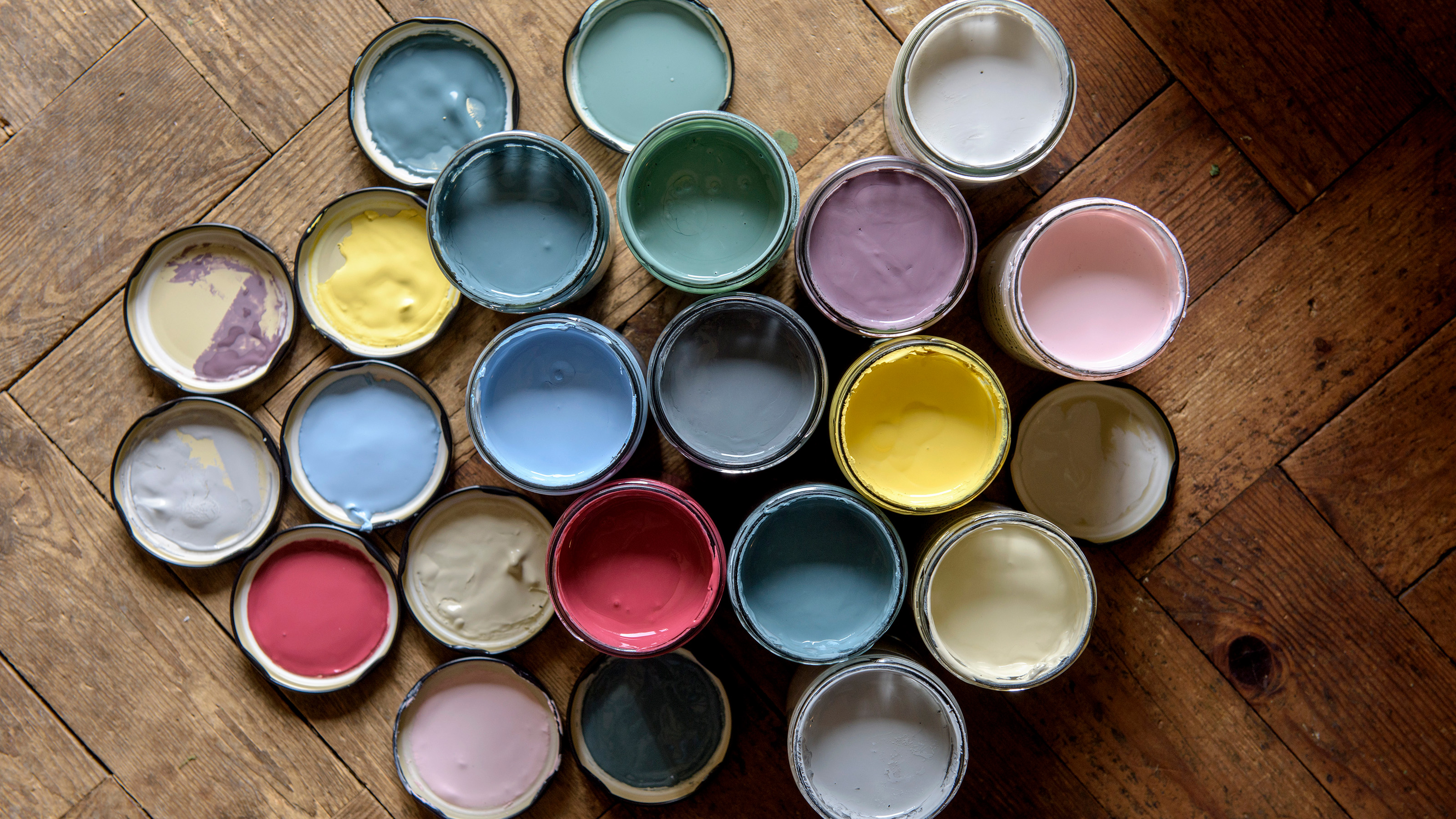 multicoloured jars of paint with lids on a wood floor