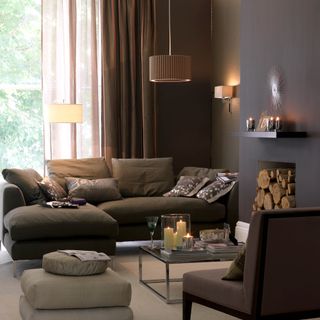 Brown living room with layered lighting, logs in fireplace and sheer curtains