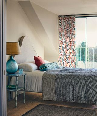 bed with yellow headboard and patchwork bedding against a wall beside a window