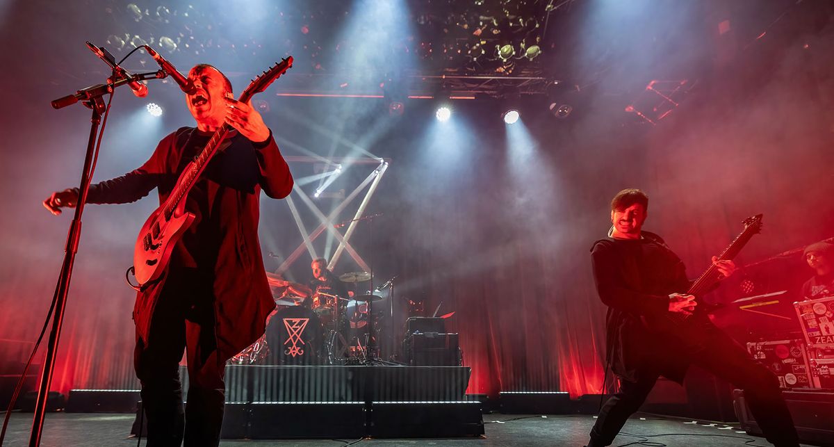 Zeal &amp; Ardor&#039;s Manuel Gagneux screams into the mic as Tiziano Volante lays down a riff on a stage bathed in red light.