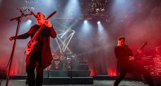 Zeal & Ardor's Manuel Gagneux screams into the mic as Tiziano Volante lays down a riff on a stage bathed in red light.