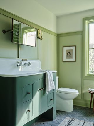 a sage green bathroom with a green vanity