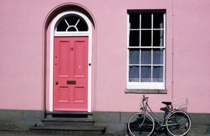 Bicycle leaning against pink house