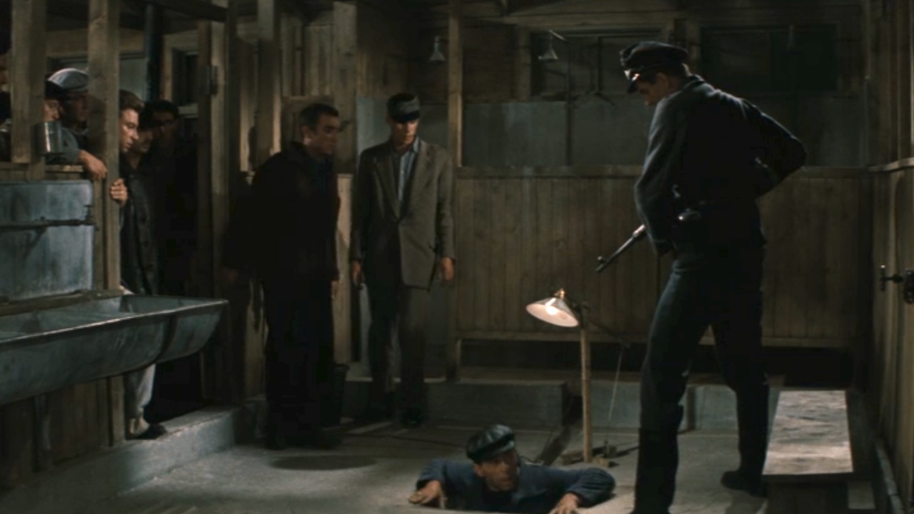 A soldier pointing a gun at a person coming up out of the tunnel in The Great Escape