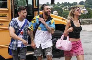 Geoff, Huss and KT are stepping out of a classic yellow American schoolbus and heading into the school with smiles on their faces