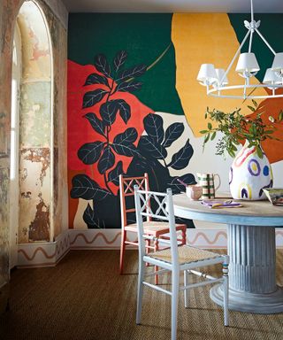 Dining room with colorful wallpaper mural, blue column dining table and chairs, painted skirting board