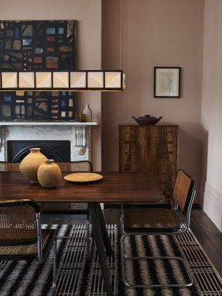 pink dining room with retro furniture, artwork, black and white rug, cube pendant light