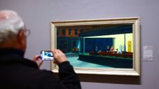 A man takes a photo of an Edward Hopper painting at the Art Institute of Chicago.
