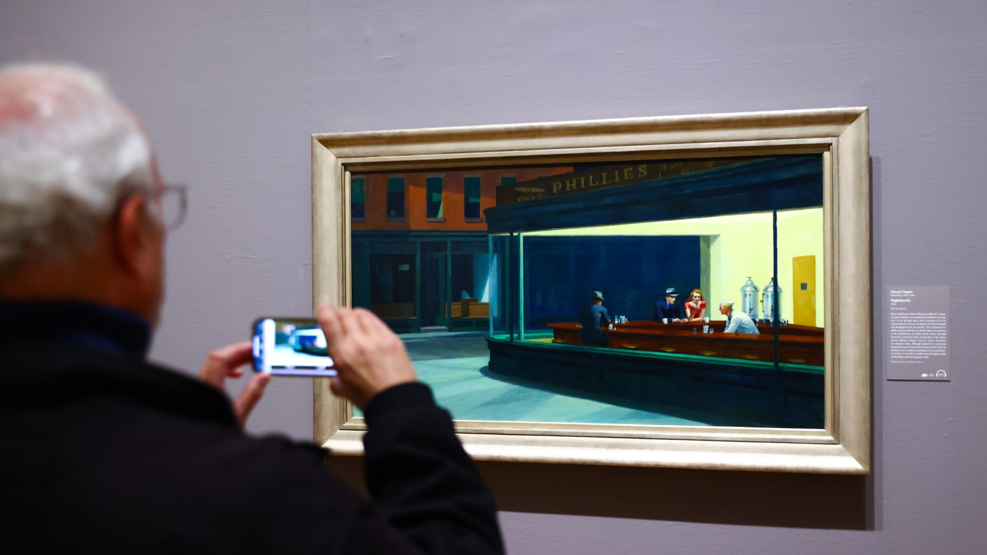 A man takes a photo of an Edward Hopper painting at the Art Institute of Chicago. 