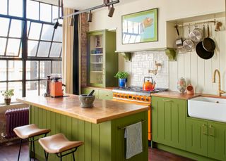 a colorful olive green kitchen with an orange range
