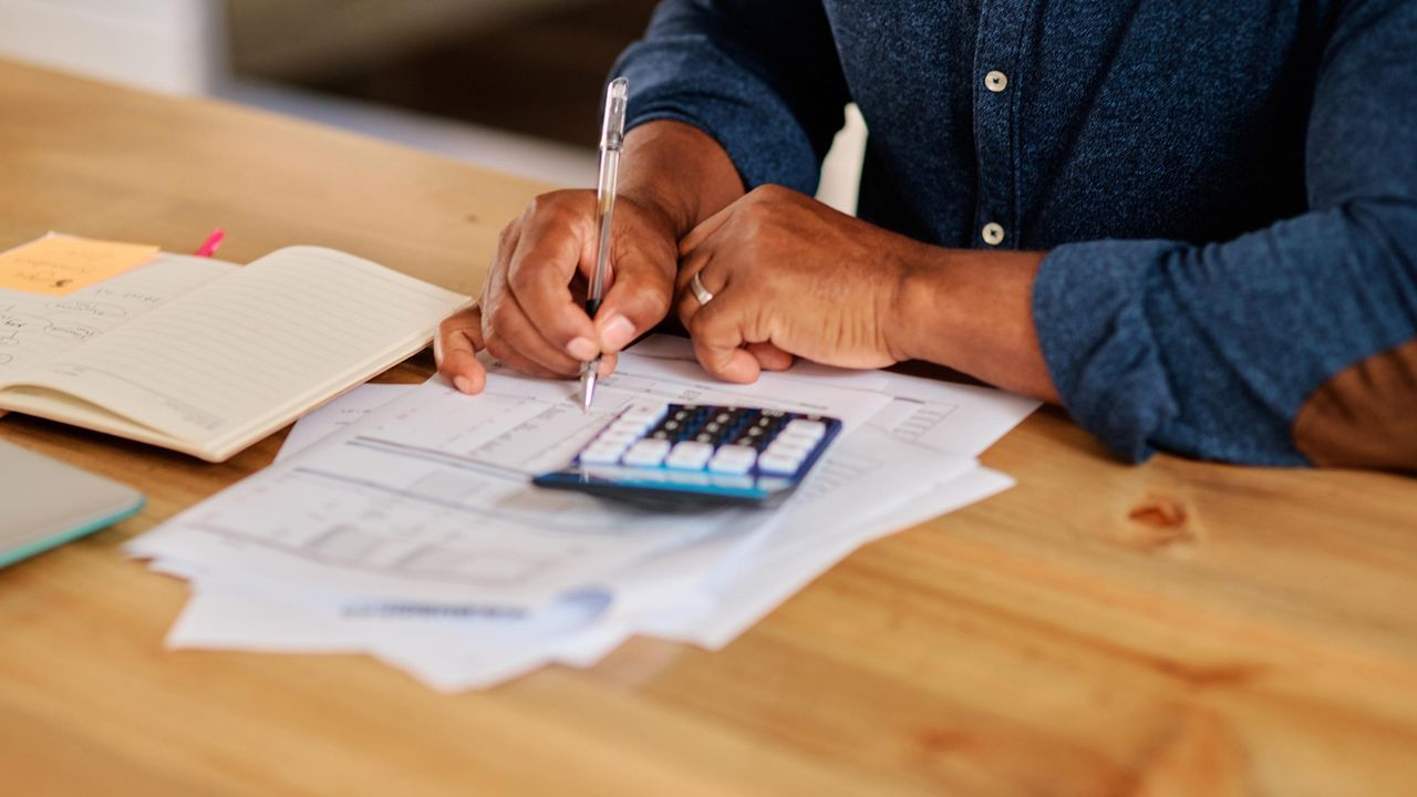 Cropped shot of an unrecognizable mature man calculating and going over his finances at home