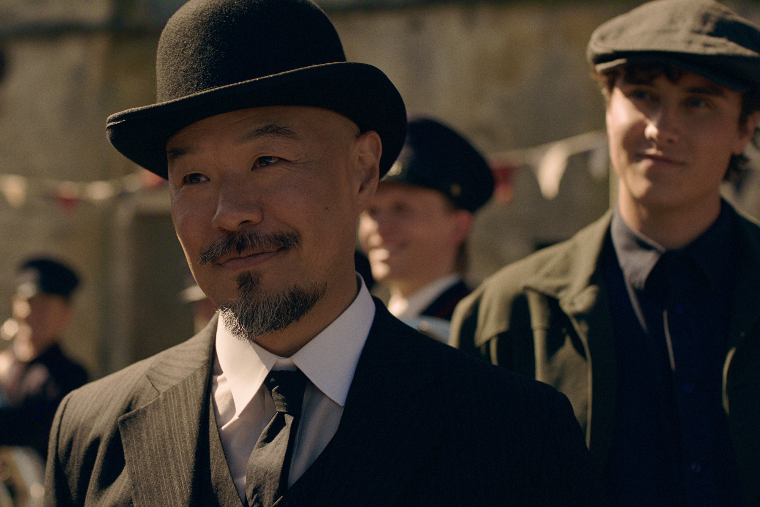 hoon lee as lee wearing a top hat and suit walking in front of joseph zada as cal trask in early 1900s era clothing in east of eden