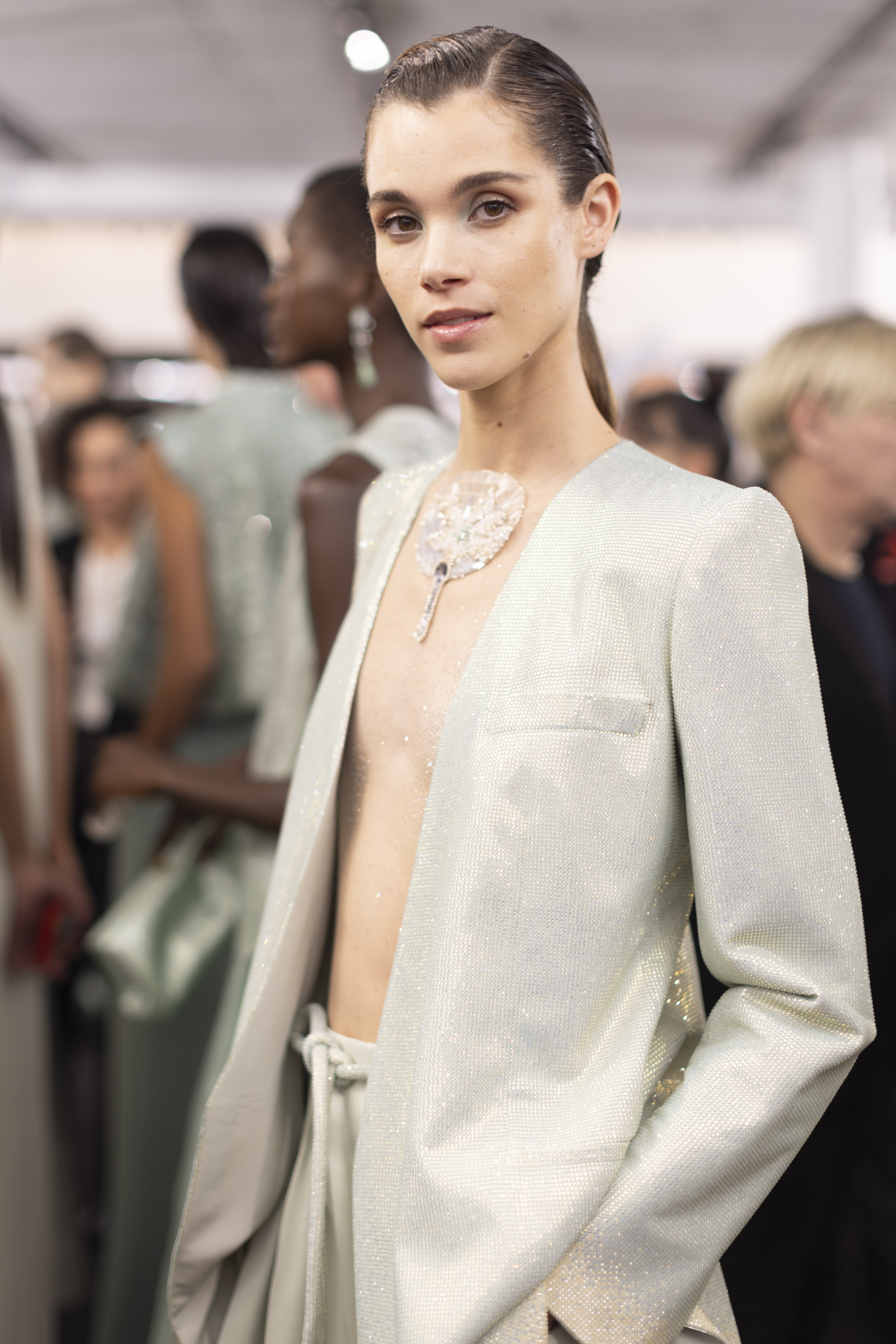 a model with dark hair poses backstage during a fashion show