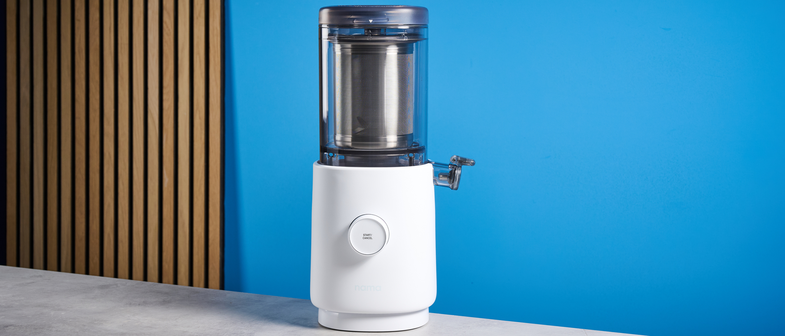 the nama m1 plant-based milk maker in white with a pitcher, blade frame, and strainer, and a pulp mat accessory with a brush