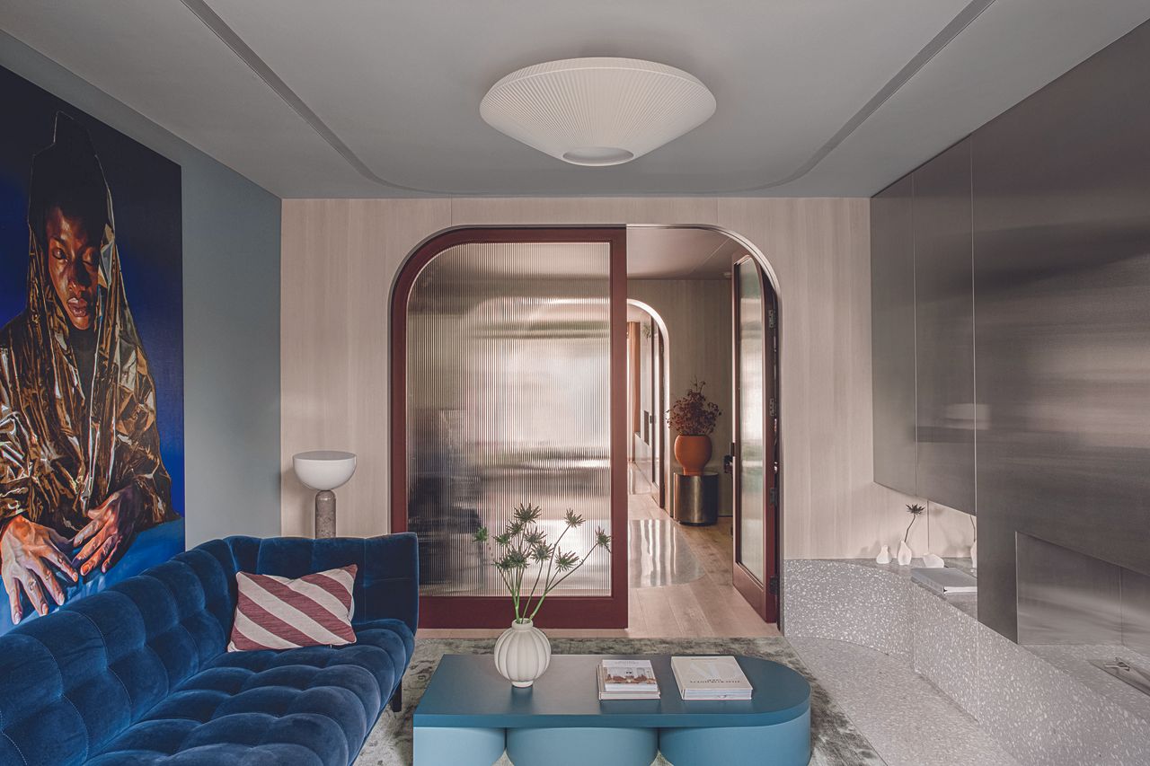 A snug living area with blue toned details and curved glass doorway