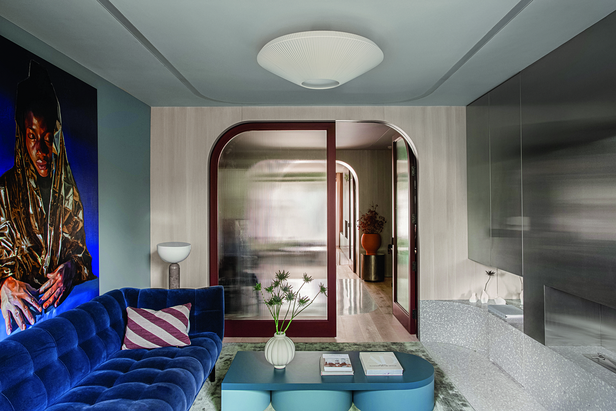 A snug living area with blue toned details and curved glass doorway