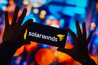 SolarWinds Corporation logo is displayed on a smartphone screen with blurry multi-colored background